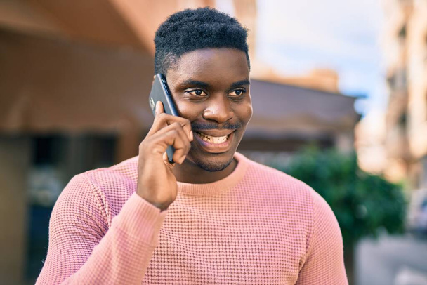 Young african american man smiling happy talking on the smartphone at the city. - Fotó, kép