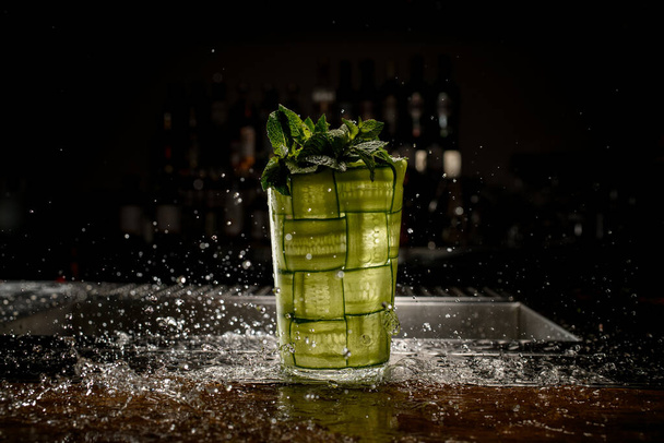 glass braided with green cucumber with splash water drops around it - Фото, зображення