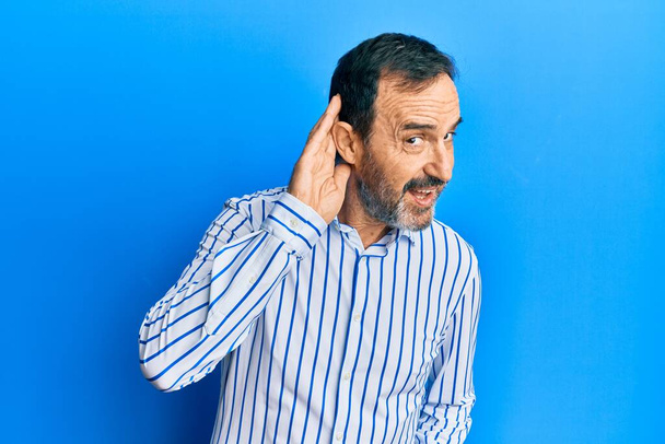 Середньовіччя іспаномовний чоловік у повсякденному одязі посміхається рукою через вухо слухаючи чутки або плітки. концепція глухоти
.  - Фото, зображення