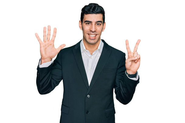 Knappe Spaanse man met zakelijke kleren aan en wijzend met vingers nummer zeven terwijl hij zelfverzekerd en gelukkig glimlacht.  - Foto, afbeelding