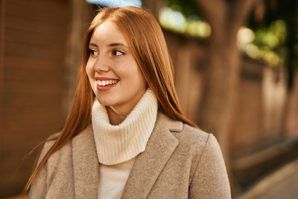 Jeune fille rousse souriant heureux debout à la ville. - Photo, image