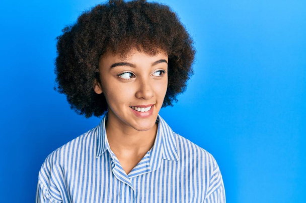 Junges hispanisches Mädchen trägt lässige Kleidung, die zur Seite schaut, entspannte Profilpose mit natürlichem Gesicht und selbstbewusstem Lächeln.  - Foto, Bild
