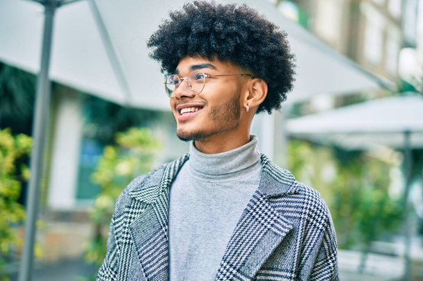 Jeune homme d'affaires afro-américain souriant heureux debout à la ville. - Photo, image