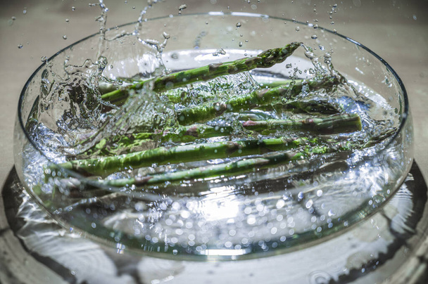 Espargos vegetais frescos e saudáveis em uma tigela de gotas de água salpicadas. Greenery comprado no mercado do fazendeiro. Alimentos ricos em vitaminas. - Foto, Imagem