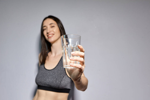 Kobieta w sportowej odzieży i ze słuchawkami bezprzewodowymi pije wodę. koncepcja zdrowego trybu życia i aktywności sportowej - Zdjęcie, obraz
