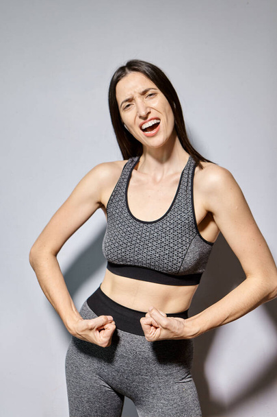 Eine Frau in Sportkleidung zeigt ihre Muskeln und lacht - Foto, Bild