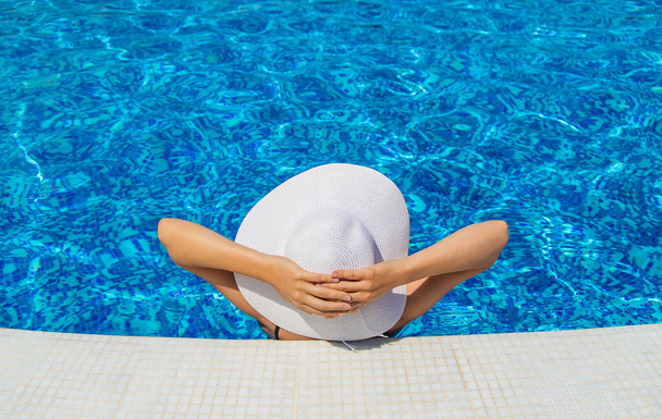 Een meisje in de buurt van het zwembad met een hoed op. Selectieve focus. Vrouw. - Foto, afbeelding