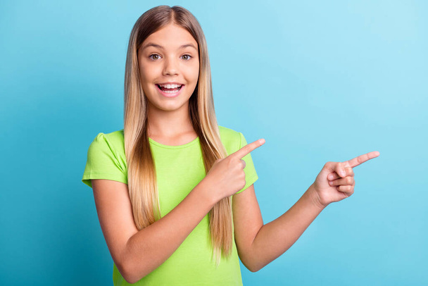 Photo of young happy cheerful good mood positive girl smiling pointing fingers in copyspace isolated on blue color background - Foto, imagen