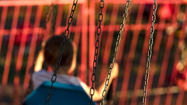 Blurred silhouette of a little child riding a carousel on chains in focus - Foto, immagini