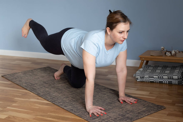 Prenatale yoga meditatie. Zwangere vrouw doet kat yoga pose thuis - Foto, afbeelding
