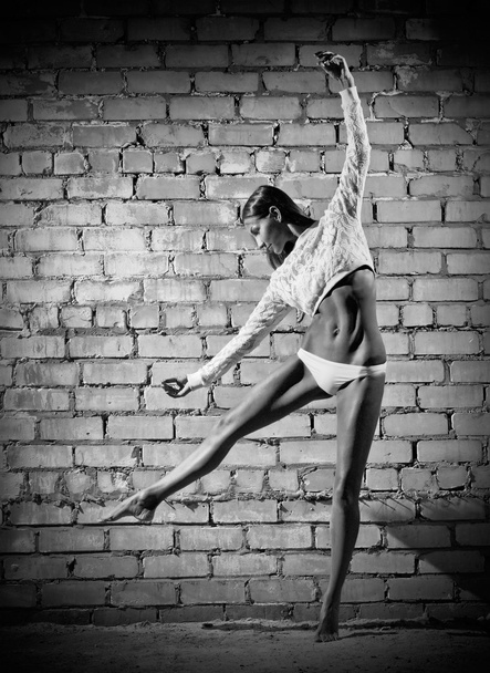 Young dancing woman on brick wall (monochrome version) - Photo, image