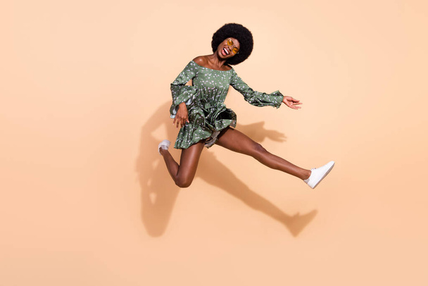 Full length profile side photo of young excited black girl happy positive smile jump play guitar isolated over beige color background - Фото, изображение