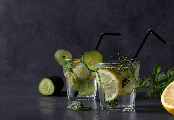 Summer fresh iced drink with mint, lemon and cucumber, healthy detox mojito cocktail on dark gray background. Space for text - Fotoğraf, Görsel