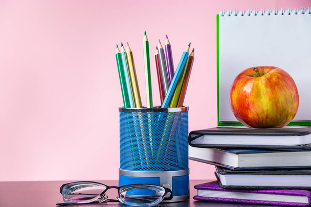 Zurück zum Schulkonzept. Schulbedarf, Bücher und Apfel auf rosa Hintergrund. Platz für Text. - Foto, Bild