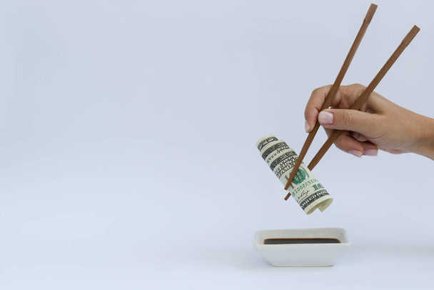 Dollars in a timber chopstick on a white with a copy space. - Фото, изображение