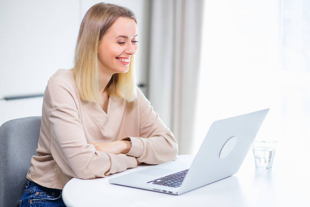 Schöne junge Frau arbeitet konzentriert mit Computer-Laptop und lächelt - Foto, Bild