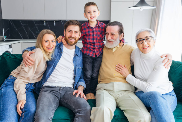 familie, geluk, generatie en mensen concept - gelukkig gezin zit op de bank thuis - Foto, afbeelding