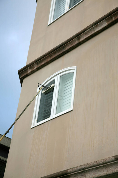 Καθαρισμός παραθύρων. Πλυντήριο παραθύρων. Υπηρεσία πλυντηρίου παραθύρων. Ένα επαγγελματικό καθαριστικό παραθύρων πλένει και ξεπλένει τα παράθυρα με Di Ionized Spot Free Water για ένα Squeekie Clean Service. Πλυντήριο παραθύρων με έναν στύλο επέκτασης. Για δωρεάν πλύσιμο και ξέπλυμα!  - Φωτογραφία, εικόνα
