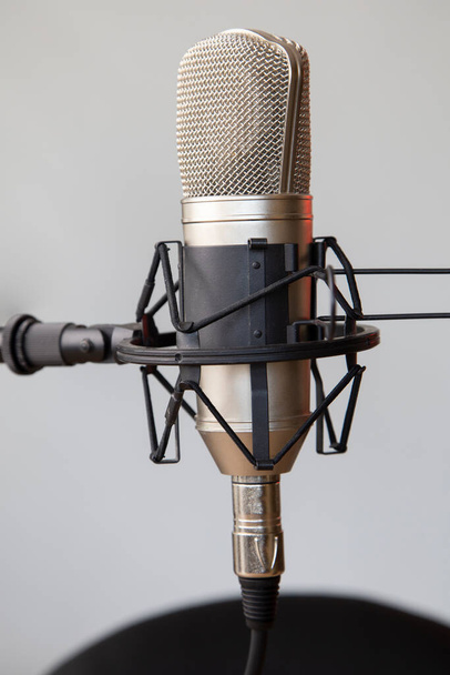 Nahaufnahme eines professionellen Mikrofons mit Stativ und Kabel, Musikinstrument im Studio, modernes Objekt - Foto, Bild