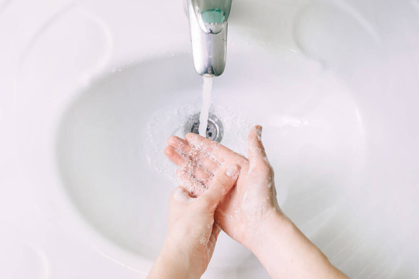 bijgesneden schot van persoon wassen handen in gootsteen - Foto, afbeelding