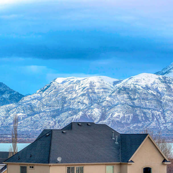 Square Suburb houses with view of blue lake and snowy mountain against overcast sky - Photo, Image