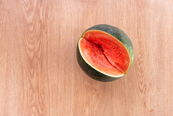 Seedless watermelon which has been cut a generous piece to cool off at ease on an oak floor background - Fotoğraf, Görsel
