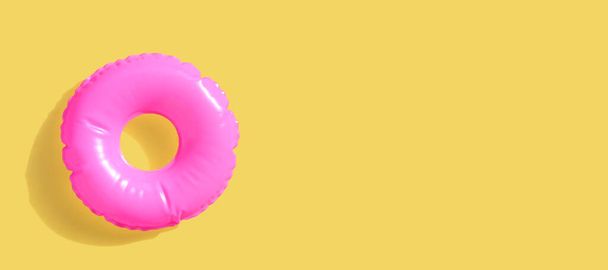 Anillo de piscina inflable rosa en superficie amarilla - Foto, Imagen