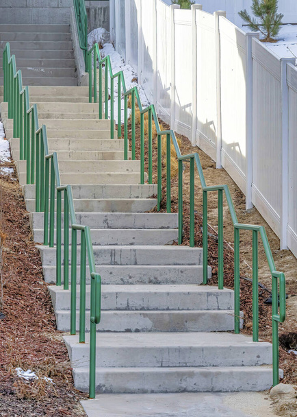 Вертикальні сусідні сходи вздовж будинків з білими дерев'яними парканами і засніженими двориками
 - Фото, зображення