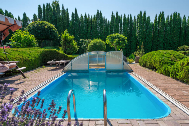 Schwimmbad und Garten mit schön beschnittenen Sträuchern und Steinen im Hinterhof. Landschaftsplanung. Hochwertiges Foto - Foto, Bild