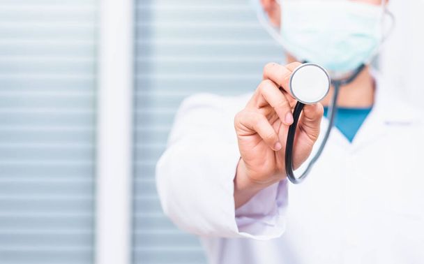 Closeup of doctor man wearing white coat standing holds his stethoscope on hand for listening check up lungs or heart, person showing medical equipment - Foto, Bild