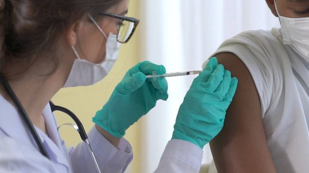 Young man visits skillful doctor at hospital for vaccination - Fotó, kép