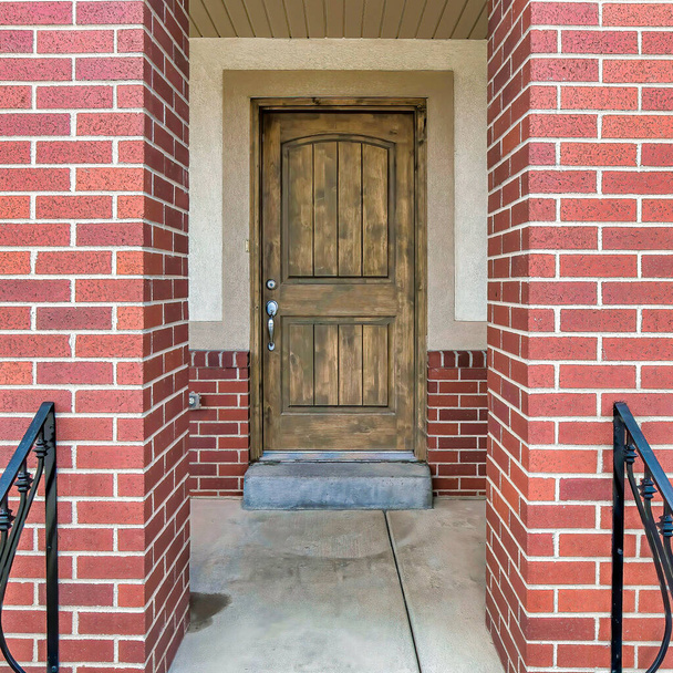 Entrée carrée avec porte d'entrée marron et meubles en métal au porche surélevé - Photo, image