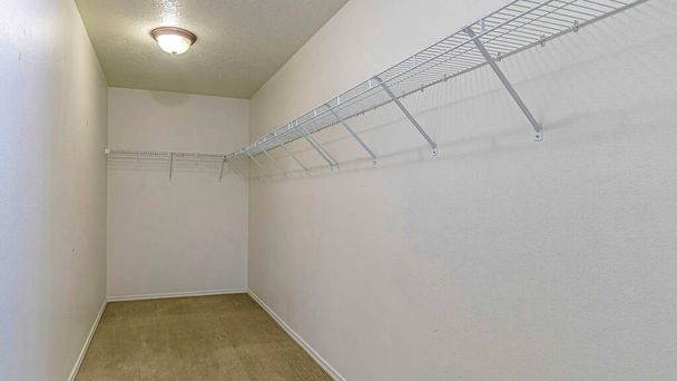 Pano prateleiras de arame montado na parede contra a parede branca de uma sala de armazenamento vazia - Foto, Imagem