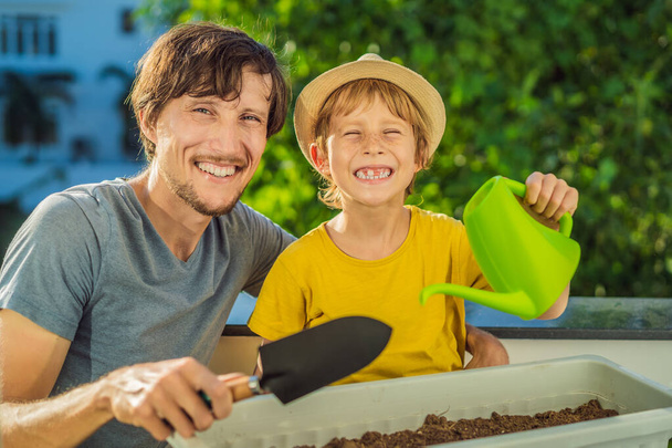 Dad and son is doing gardening on his balcony. Natural development for children - Foto, afbeelding