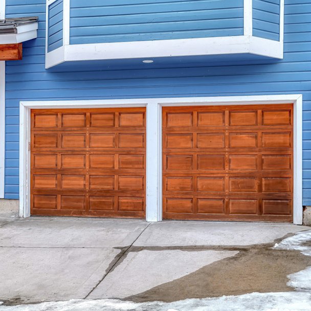 Exterior cuadrado de la casa con pared azul y adjunto garaje para dos coches con puertas marrones - Foto, Imagen
