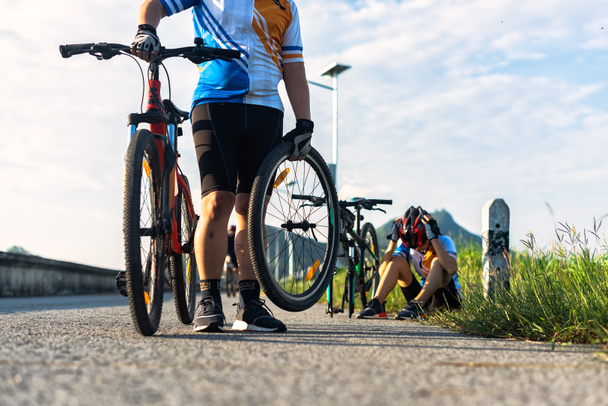 女性のサイクリングは平らなタイヤの修理が必要なときに問題があります自転車の仲間が車輪を取るのを助け - 写真・画像