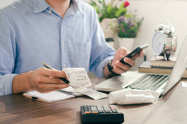 Male investor using phone and calculating bills in home office Check about expenses in investment, business, taxes, pay employees. - Fotoğraf, Görsel