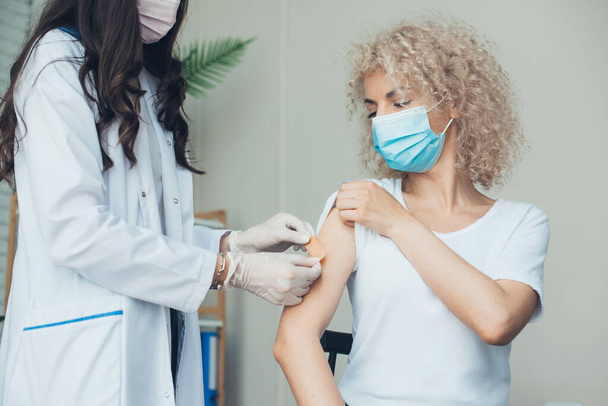 женщина получает вакцинацию. счастливая девушка защищена вакциной. оборудованная медсестра. - Фото, изображение