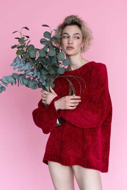 young beautiful woman posing in a red sweater in the studio - Фото, зображення