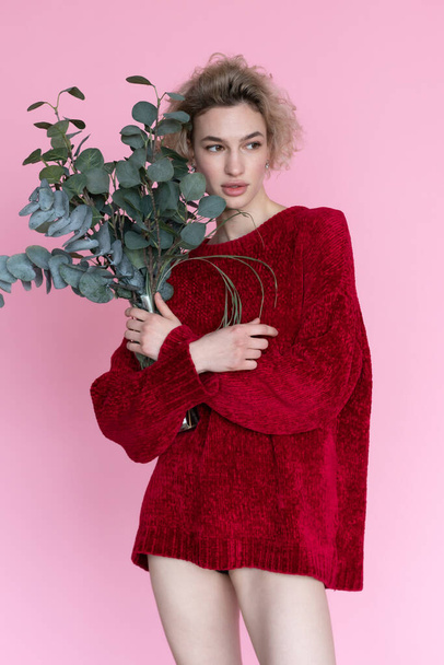 young beautiful woman posing in a red sweater in the studio - 写真・画像