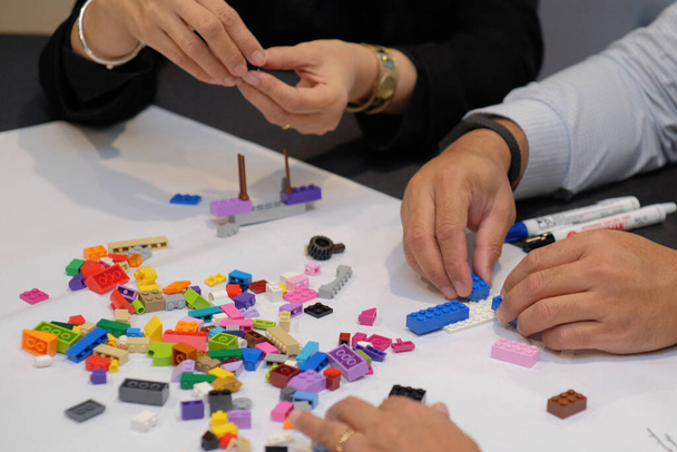 Крупный план рук взрослых, играющих в лего, как симуляция разработки бизнес-стратегии и развития человеческих ресурсов. - Фото, изображение