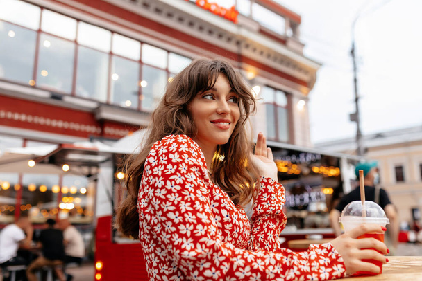 Ritratto ravvicinato di attraente ragazza affascinante con i capelli castani a riposo in città con bevanda estiva sullo sfondo della luminosa terrazza estiva. Foto di alta qualità - Foto, immagini