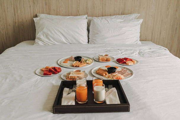 Hotel complimentary breakfast served on white bed. - Foto, afbeelding