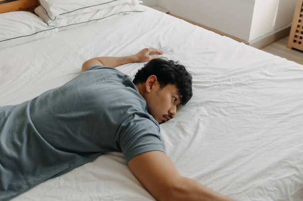 Tired man is lying on the bed as he out of energy. - Foto, imagen