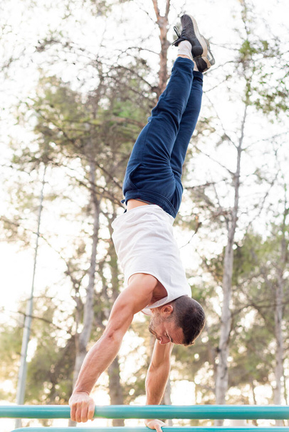 Man doing handstand on bars in the park. - Foto, afbeelding