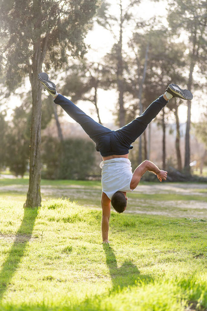 Gymnastic man handstand on one hand doing acrobatic posture - Foto, afbeelding