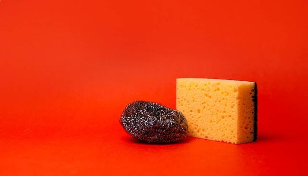 sponge and metal mesh for cleaning on a red background. - Photo, Image