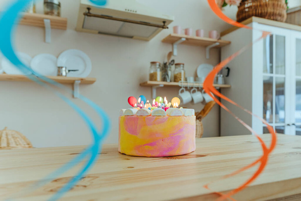 День народження торт зі свічками у вигляді літер З днем народження прикрашений їстівними цукровими кульками на дерев'яному столі на кухні. Вибірковий фокус
. - Фото, зображення