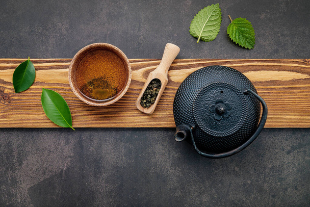 Black cast iron tea pot with herbal tea set up on dark stone background. - Photo, Image