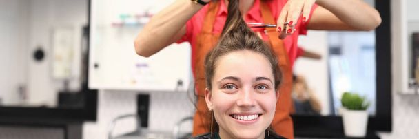Portrait de femme souriante dans un salon de coiffure, qui lui coupe les cheveux - Photo, image